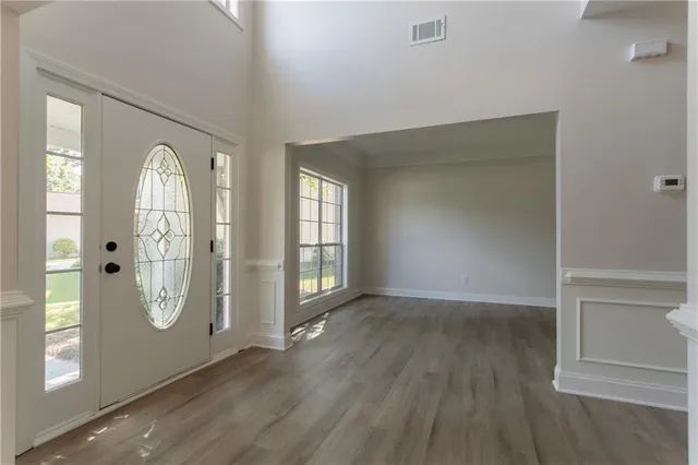 an empty room with wooden floor mirror and windows