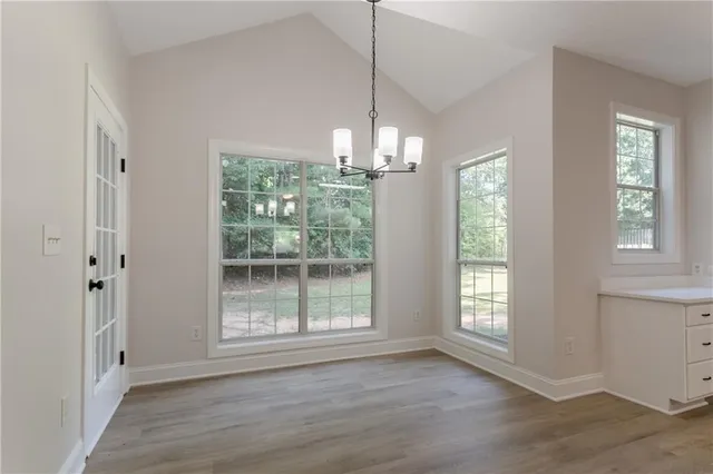 a view of a big room with wooden floor chandeliers and kitchen view