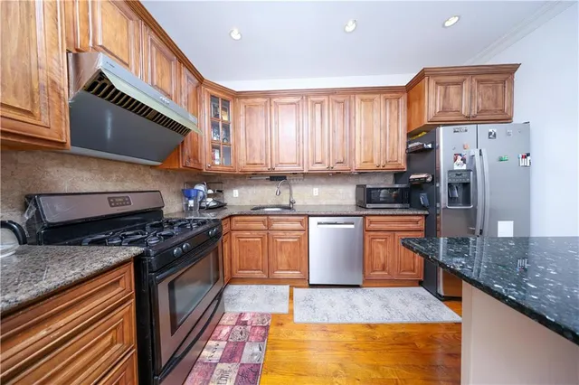 a kitchen with stainless steel appliances granite countertop a stove a sink dishwasher and a refrigerator