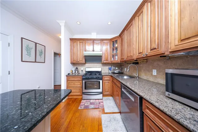 a kitchen with stainless steel appliances granite countertop a stove a sink and a microwave