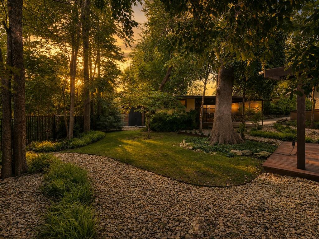 13321 Purple Sage Road Dallas, TX 75240 - Photo 2 of 30 AI Augmented Expansive landscaped grounds featuring mature trees, a manicured lawn, a gravel pathway, and a wooden deck structure