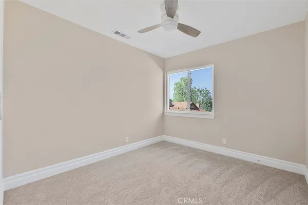an empty room with windows and ceiling fan