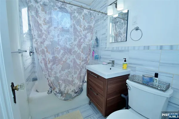 a bathroom with a granite countertop sink a toilet and shower