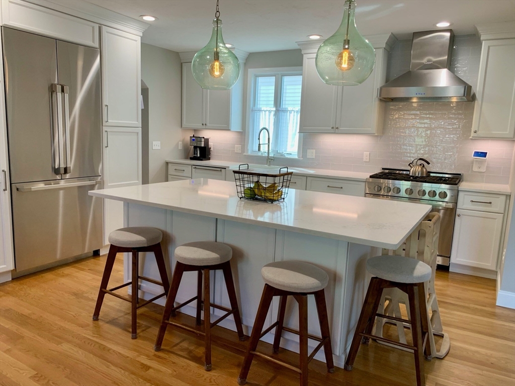 15 Maypole Road Quincy, MA 02169 - Photo 7 of 28 a kitchen with stainless steel appliances a dining table chairs stove and refrigerator