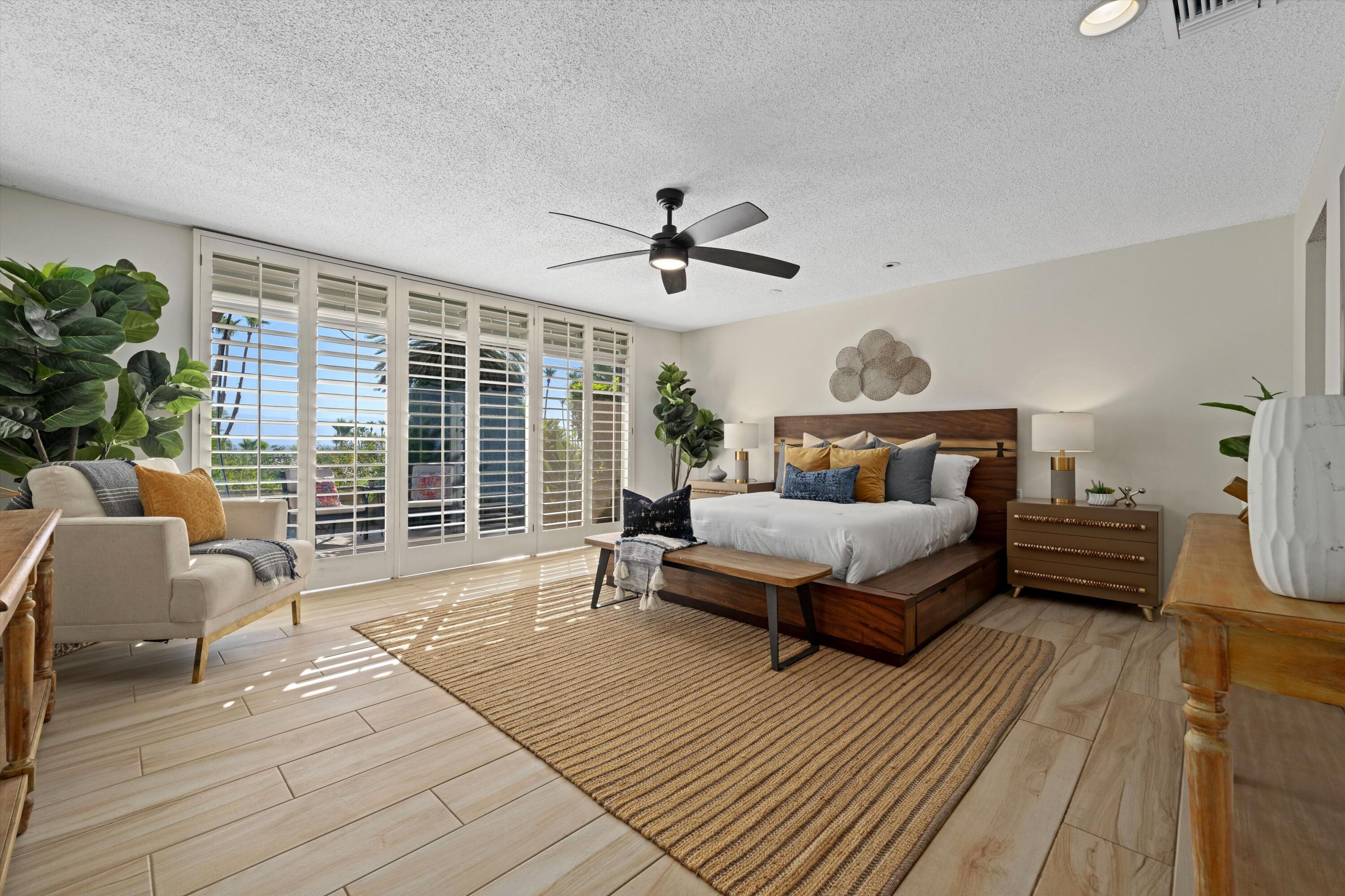 40270 Paseo Del Rey Rancho Mirage, CA 92270 - Photo 21 of 41 a spacious bedroom with a bed a couch and a large window with wooden floor