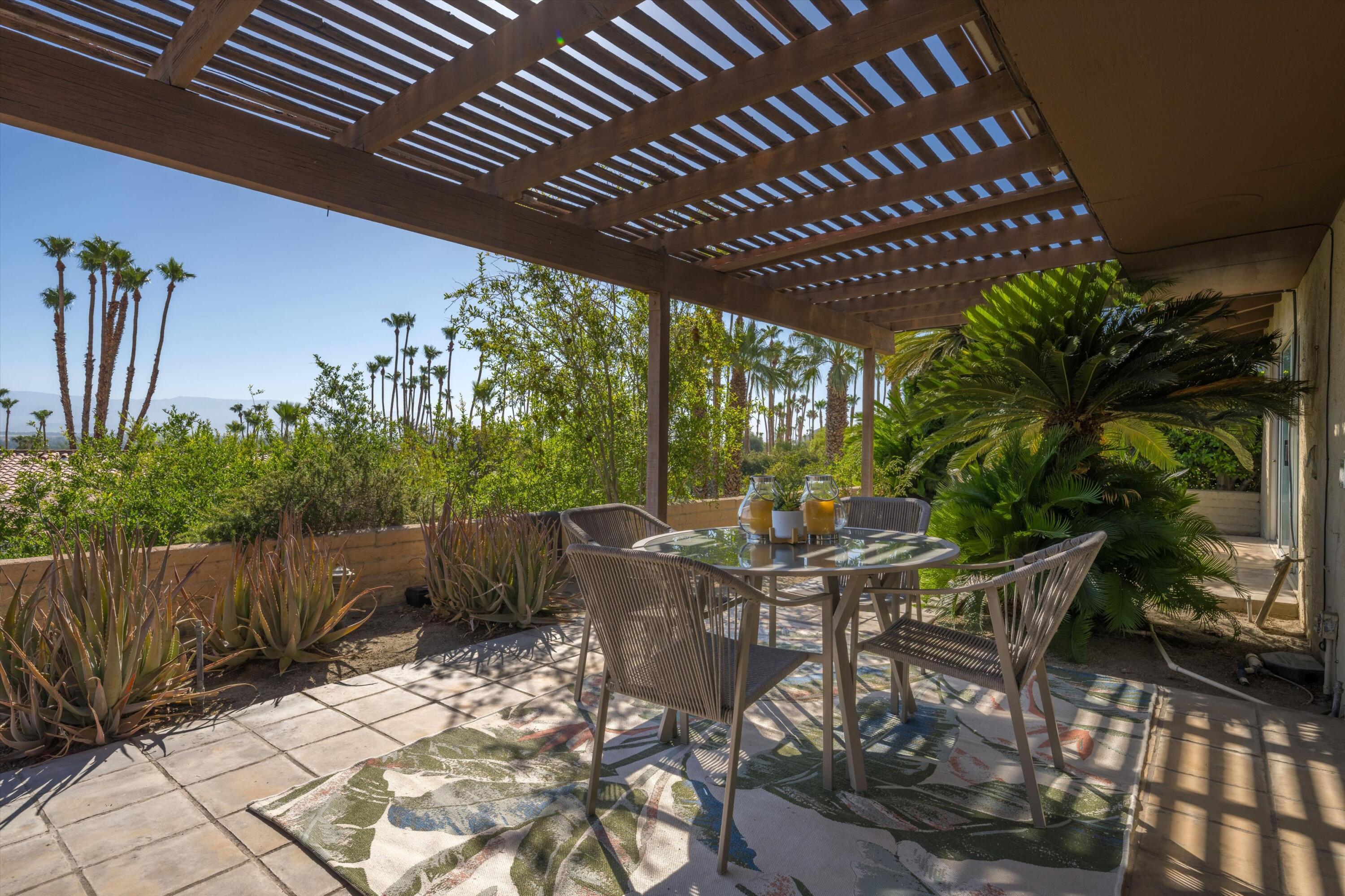 40270 Paseo Del Rey Rancho Mirage, CA 92270 - Photo 40 of 41 a view of a patio with table and chairs with wooden floor and fence with plants