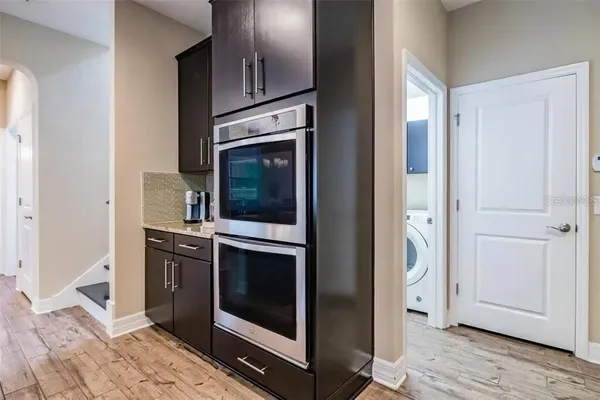 a open kitchen with stainless steel appliances granite countertop a stove top oven a refrigerator a dining table and chairs with wooden floor