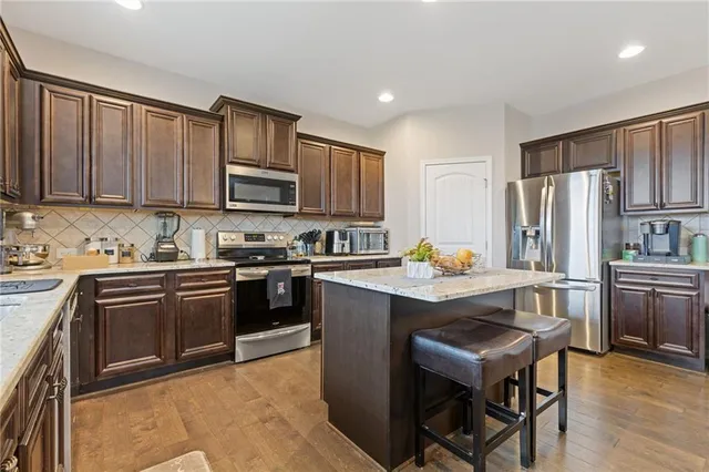 a kitchen with stainless steel appliances granite countertop a stove refrigerator sink and cabinets