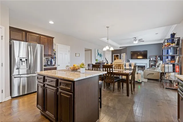 a kitchen with stainless steel appliances granite countertop a table chairs and a refrigerator