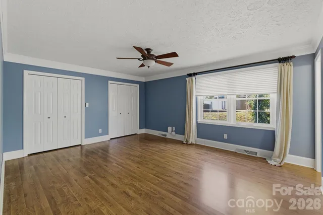 a view of an empty room with a window and wooden floor