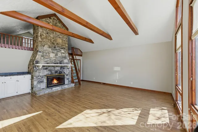 a view of empty room with fireplace and wooden floor