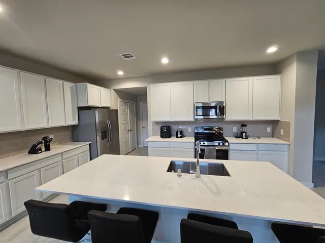 a kitchen with kitchen island a sink a stove a refrigerator and white cabinets