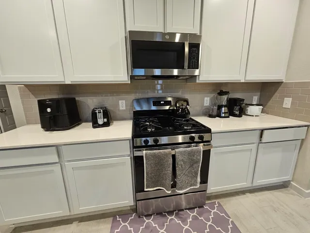 a kitchen with granite countertop white cabinets stainless steel appliances and a sink