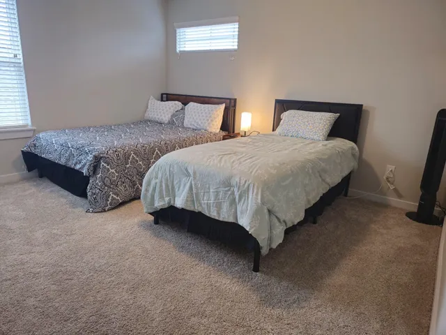 a spacious bedroom with two beds and a lamp