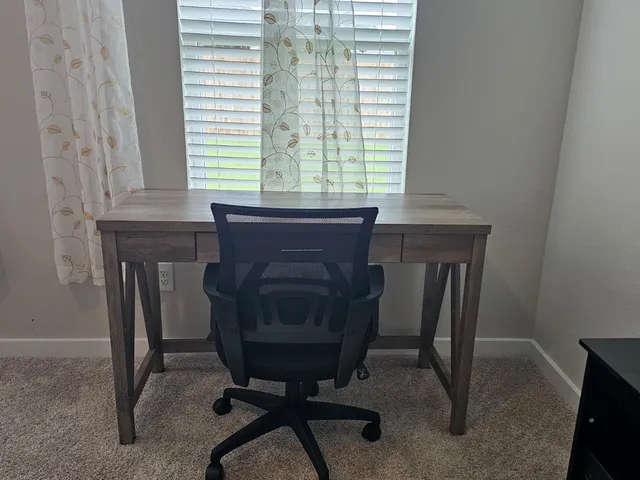 a view of a workspace with furniture and a window