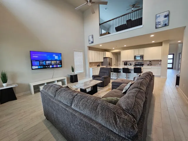 a living room with furniture kitchen view and a wooden floor