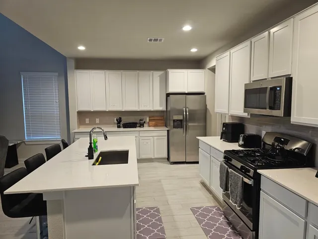a kitchen with a sink stainless steel appliances and white cabinets
