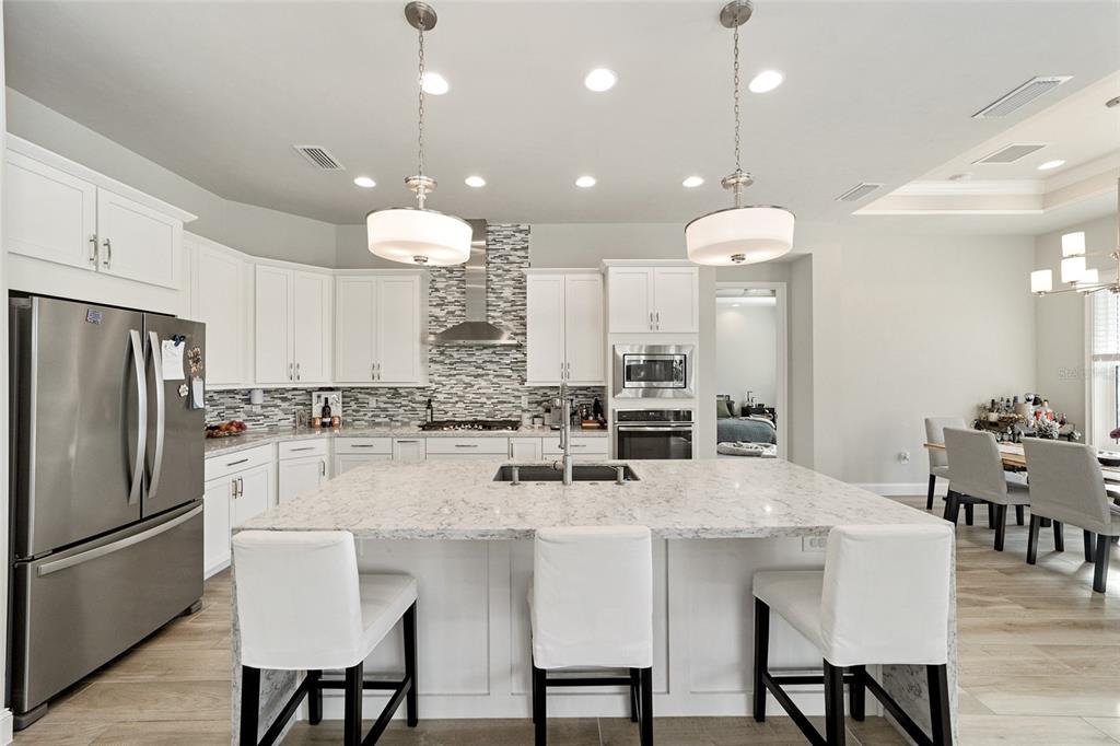 11895 Southwest 33 Lane Gainesville, FL 32608 - Photo 24 of 67 a kitchen with stainless steel appliances a dining table chairs refrigerator and microwave