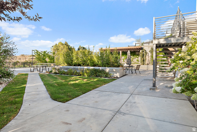 912 North Loafer Canyon Road Elk Ridge, UT 84651 - Photo 67 of 98 Expansive concrete patio with integrated landscaping, a raised planting bed, and a metal staircase with railing