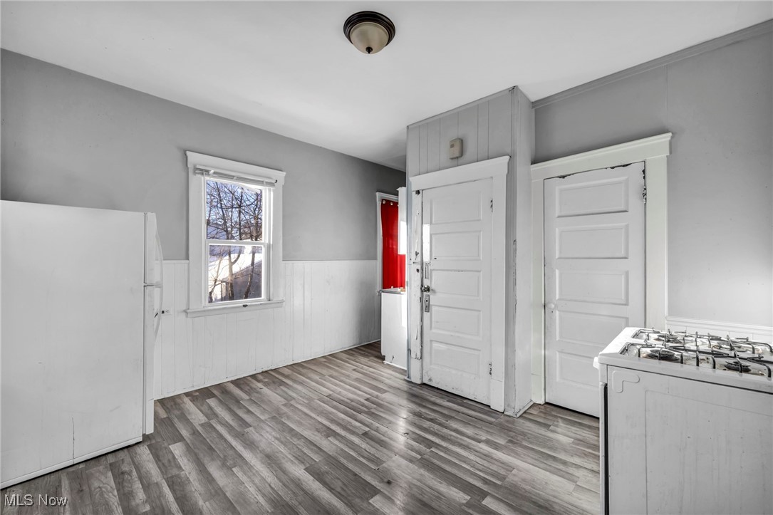 3405 Roehl Avenue Cleveland, OH 44109 - Photo 23 of 50 Kitchen with white appliances, wood finished floors, a wainscoted wall, and white cabinets