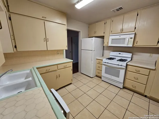 a kitchen with white cabinets and white appliances
