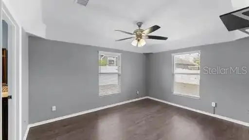 a view of empty room with wooden floor and fan