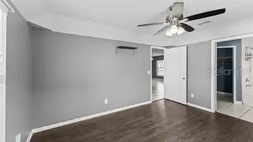 an empty room with wooden floor fan and windows