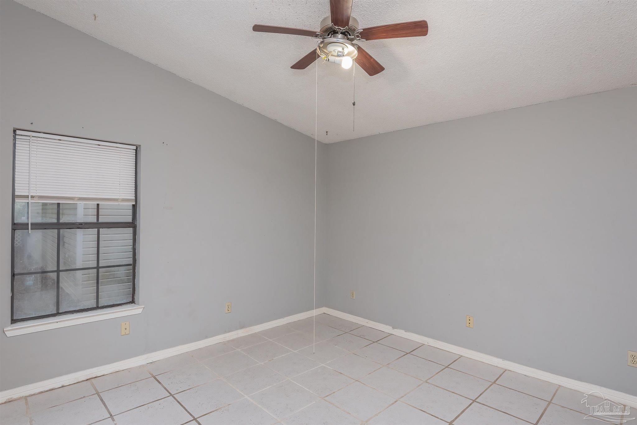 8210 Kipling Street, Unit A Pensacola, FL 32514 - Photo 5 of 13 an empty room with windows and fan