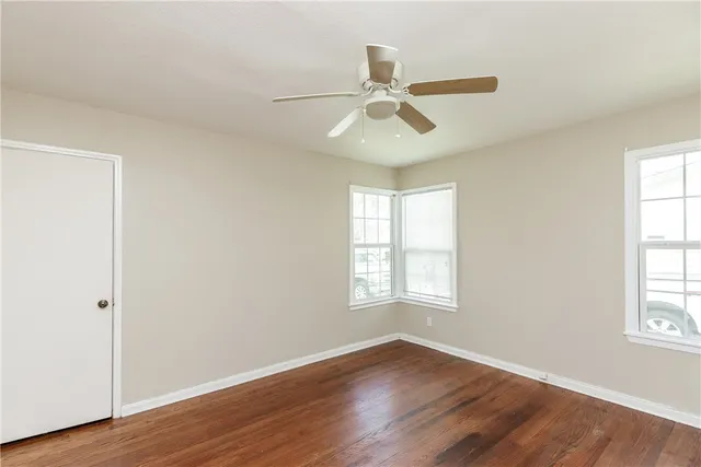 an empty room with wooden floor and ceiling fan