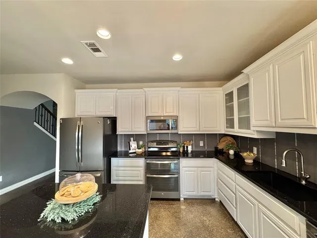 a kitchen with granite countertop stainless steel appliances and refrigerator
