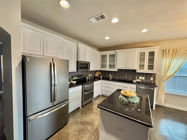 a kitchen with kitchen island a counter top space stainless steel appliances and cabinets
