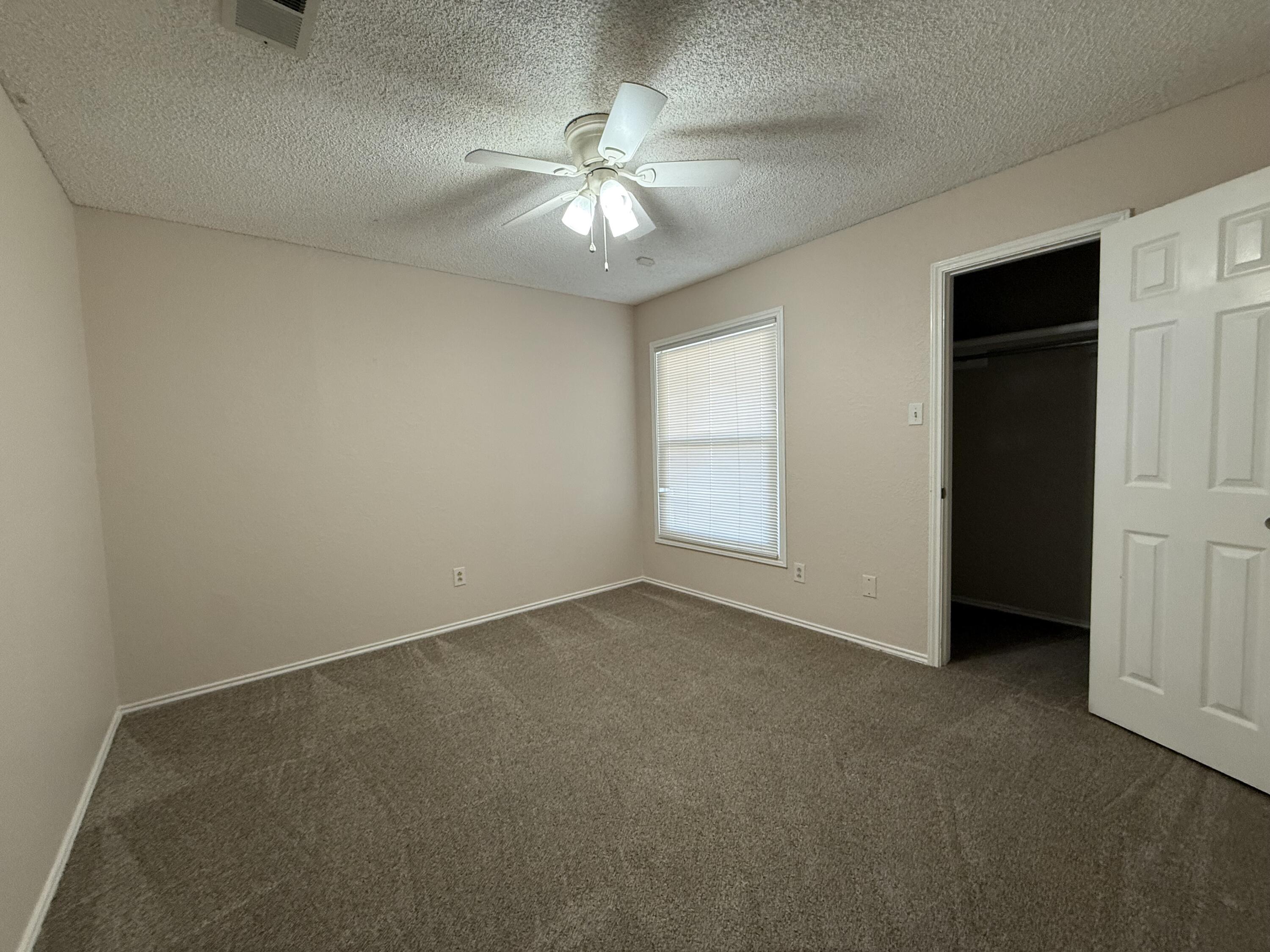 5729 89th Street Lubbock, TX 79424 - Photo 13 of 15 an empty room with chandelier fan and windows
