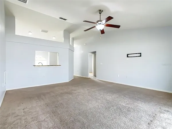 a view of a big room with a ceiling fan and windows