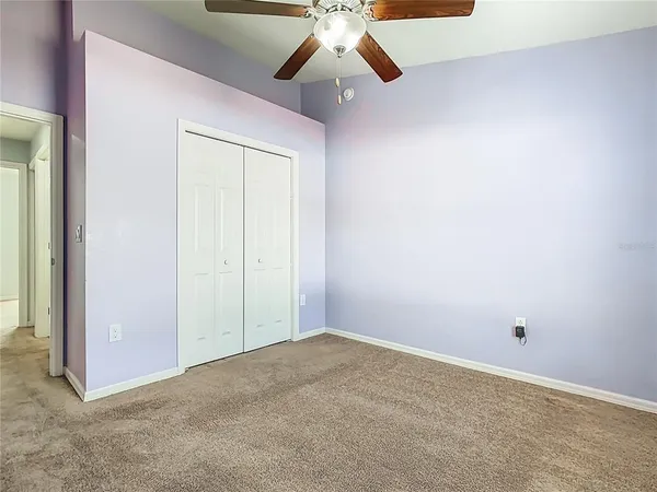 an empty room with chandelier fan and windows