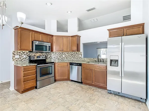 a kitchen with granite countertop a refrigerator stove and microwave
