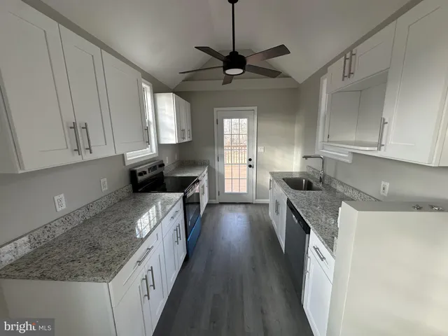 a kitchen with granite countertop a sink a counter space appliances and cabinets