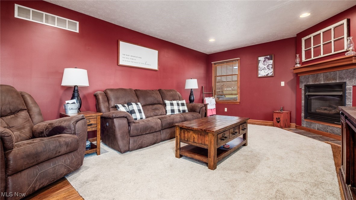 62960 James Road Cambridge, OH 43725 - Photo 12 of 40 Living area featuring wood finished floors, a tile fireplace, a textured ceiling, and recessed lighting
