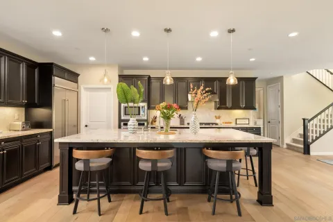 a kitchen with stainless steel appliances kitchen island granite countertop a table chairs sink and cabinets