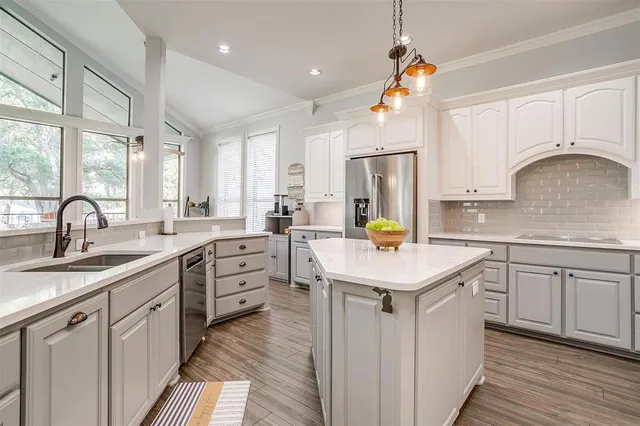 a kitchen with white cabinets appliances and a window