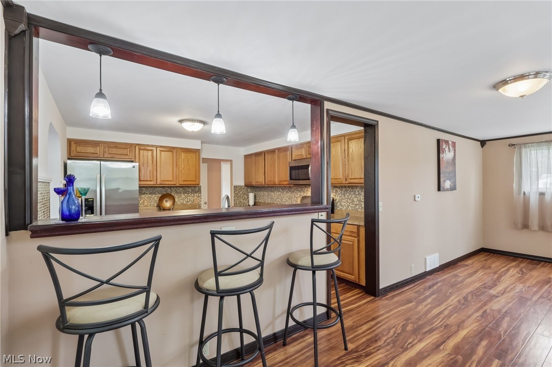 4188 Manchester Road Perry, OH 44081 - Photo 8 of 41 Kitchen pass-through with pendant lighting, wood-finish flooring, and built-in cabinetry