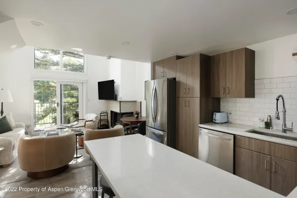 a kitchen with a refrigerator a sink dishwasher a dining table and chairs with wooden floor