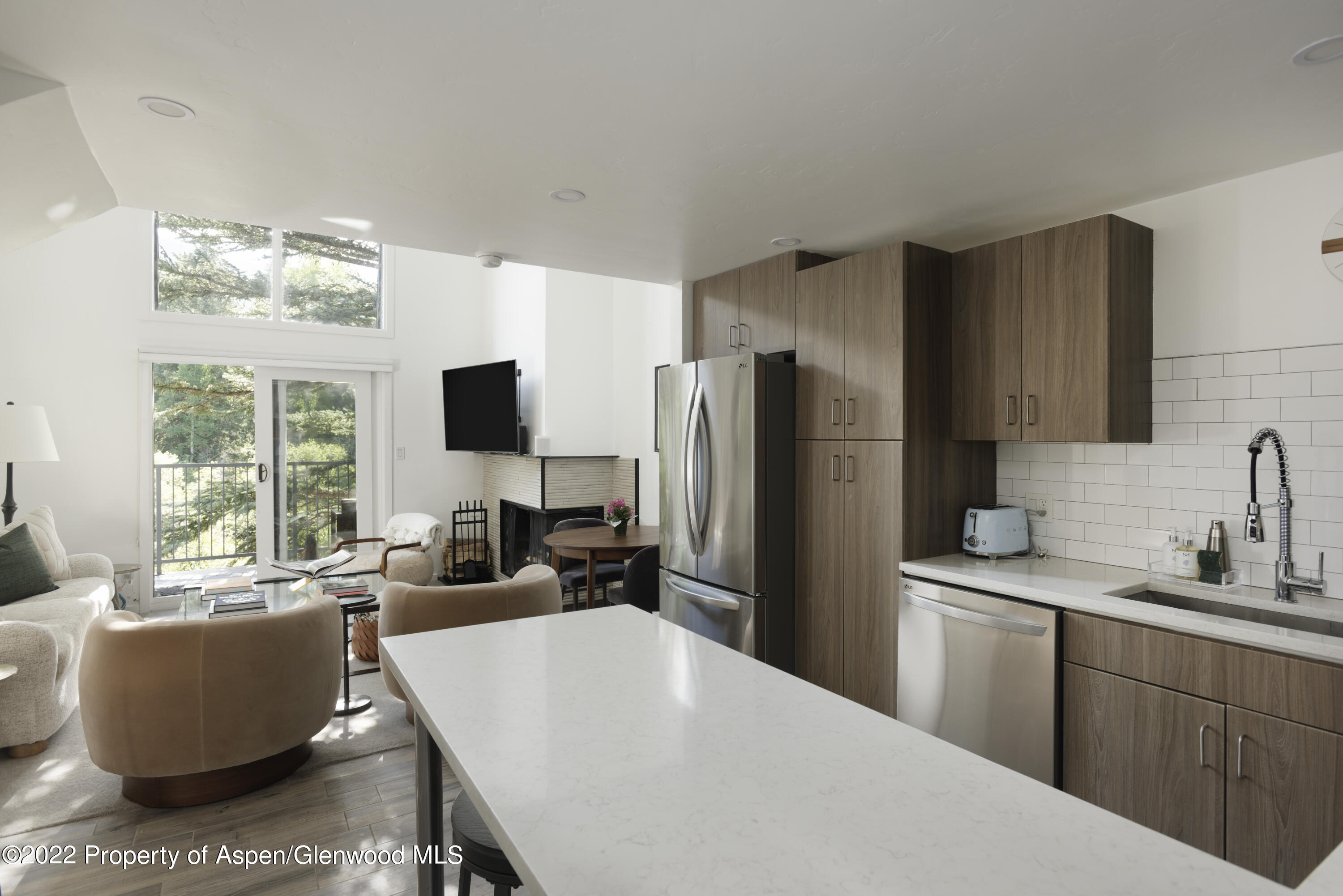 1050 Waters Avenue, Unit 14 Aspen, CO 81611 - Photo 4 of 19 a kitchen with a refrigerator a sink dishwasher a dining table and chairs with wooden floor