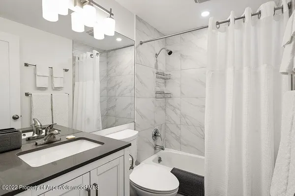 a bathroom with a sink vanity granite toilet and shower