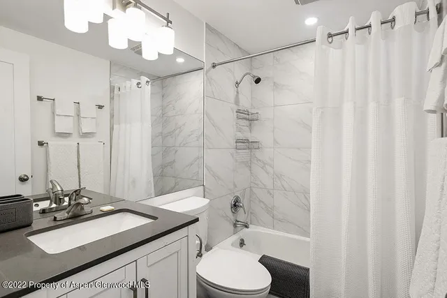 a bathroom with a sink vanity granite toilet and shower