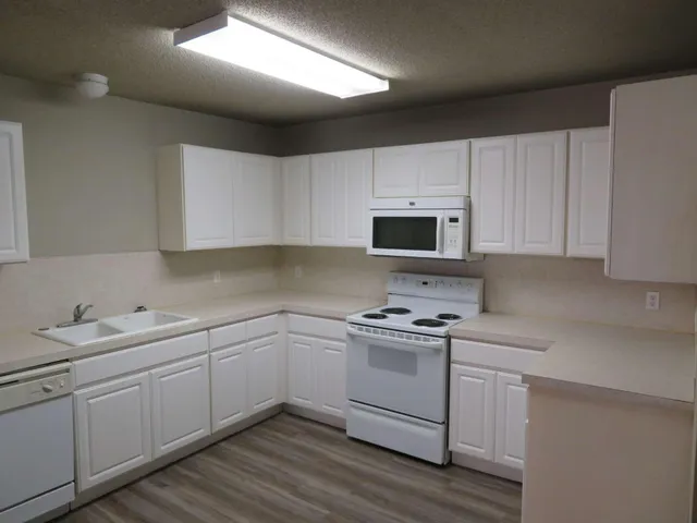 a kitchen with a sink white cabinets and white appliances