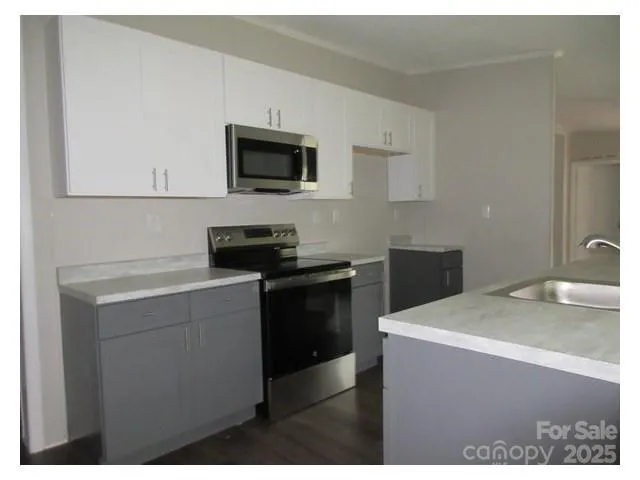 a kitchen with a sink and a stove top oven with wooden floor