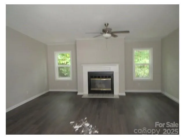 an empty room with wooden floor fireplace and windows
