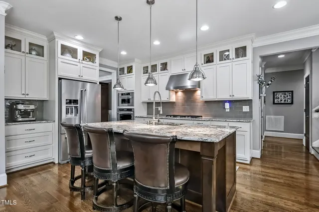 a kitchen with stainless steel appliances granite countertop a stove a refrigerator oven a sink with island and chairs