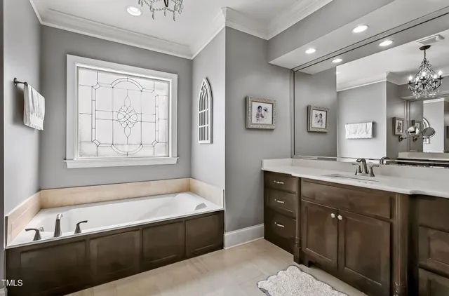 a bathroom with a tub a sink double vanity and a window