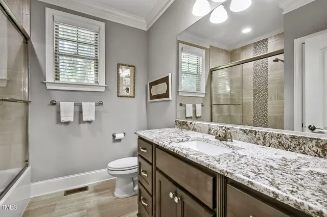 a bathroom with a granite countertop sink toilet a large mirror and shower